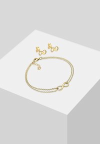 Gold-tone infinity bracelet with dual chains and a lobster clasp; matching infinity stud earrings feature a decorative design.