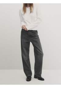 Sorte denim bredbenede jeans med høj talje, forlommer og en falmet finish, parret med en langærmet hvid skjorte og sorte sko.