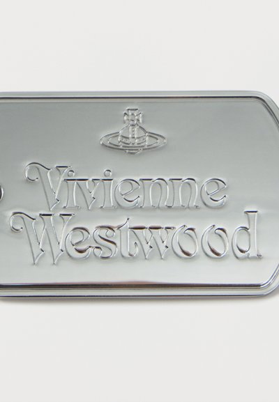 Μεταλλική ταμπέλα με εξογκωμένο λογότυπο Vivienne Westwood και σύμβολο σφαίρας σε ανοιχτό φόντο.