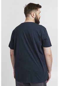 Mørkeblå bomull T-skjorte med korte ermer og rund hals, sett bakfra, med en avslappet passform og glatt tekstur.