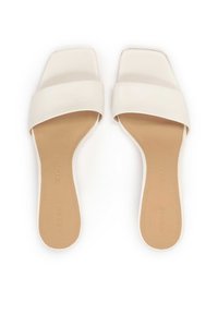 Witte instap sandalen met vierkante tenen, brede gladde bandjes en een platte beige zool. De binnenvoering heeft zichtbare stiksels en branding.