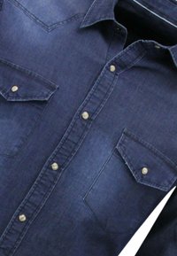 Donkerblauwe spijkerblouse met een kraag, een voorzijde met knoopsluiting, twee borstzakken met puntige kleppen en metalen knopen.