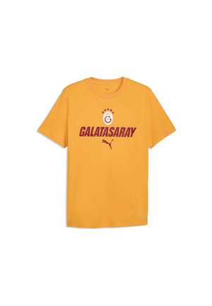 Żółta koszulka z krótkim rękawem z czerwonym tekstem "GALATASARAY", logo Puma i emblematem klubu sportowego Galatasaray z pięcioma gwiazdkami nad nim.