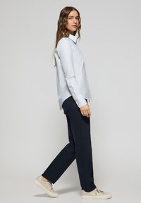 Ljust blårandig skjorta med knappar, långa ärmar, i kombination med mörknavybyxor och beige skor. Släta, jämna texturer och klassisk design.