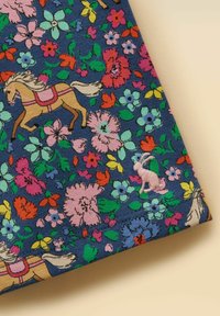 Modrá látka s barevným květinovým potiskem, se světlým koněm s růžovým sedlem a malou růžovou vyšívanou opičkou u lemu.