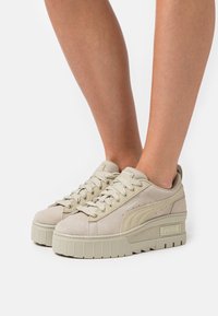 Sneaker platform beige in suede con suola in gomma testurizzata, caratterizzate da punta arrotondata e design con lacci, con logo in rilievo sul lato.