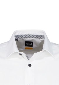 Camicia bianca con colletto strutturato, dotata di un accento a motivo all'interno e un'etichetta con logo. Tessuto testurizzato con bottoni scuri.