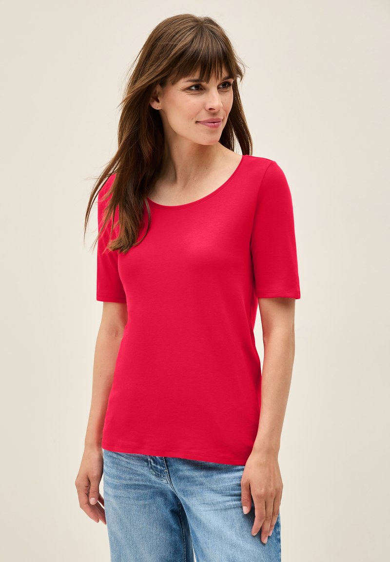 Rød kortærmet t-shirt med rund halsudskæring, glat tekstur og en tætsiddende pasform. Sæt sammen med lyseblå denimjeans.