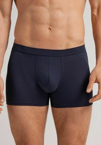 Námořnické modré boxerky vyrobené z hladkého materiálu, s předním kapsičkovým prostorem, elastickým pasem a plochými švy pro pohodlí a dokonalé padnutí.