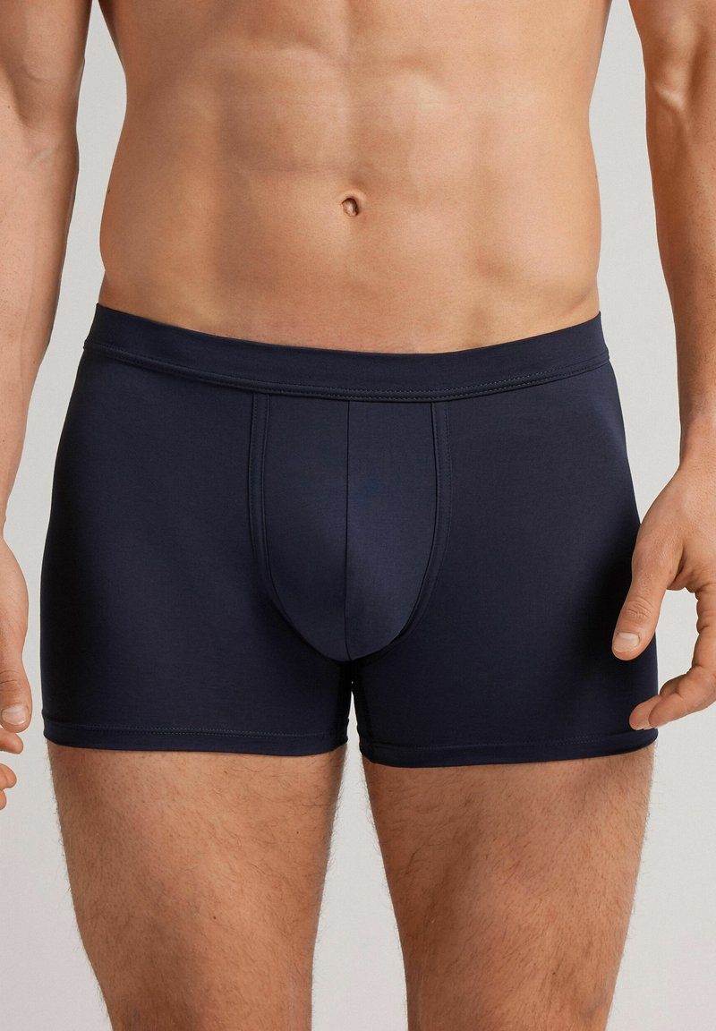 Námořnické modré boxerky vyrobené z hladkého materiálu, s předním kapsičkovým prostorem, elastickým pasem a plochými švy pro pohodlí a dokonalé padnutí.