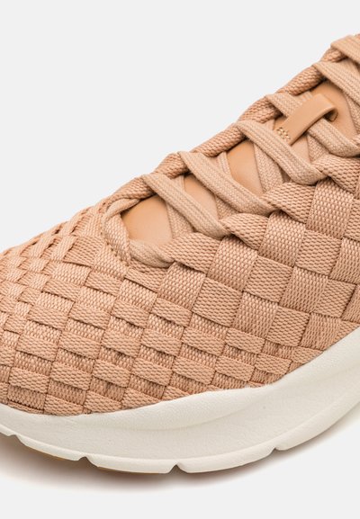 Gewebter Textilsneaker in hellem Braun mit strukturiertem Obermaterial, ausgestattet mit einer verstärkten Lederüberlage und einer weißen Gummisohle.