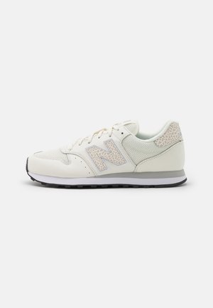 Biało-szare buty sportowe New Balance z panelami z siateczki, akcentami w panterkę na logo i pięcie oraz czarną gumową podeszwą.