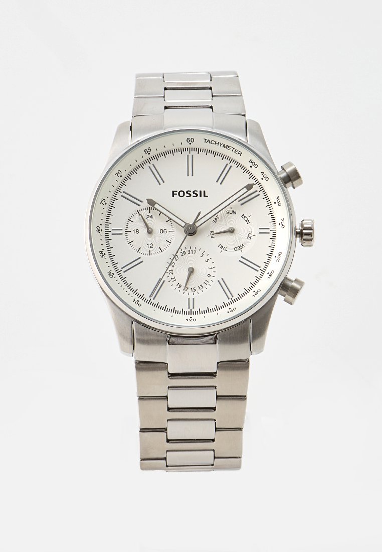 Montre chronographe en acier inoxydable argenté avec un cadran blanc, trois sous-cadrans, tachymètre et bracelet à maillons. Nom de la marque "FOSSIL" affiché.
