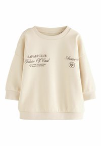 Kreemjas värvi sweatshirts laia kaela, langevate õlgadega, soonikkoes mansettide ja prinditud pruunide tekstidega, millel on ringikujuline logo detail.