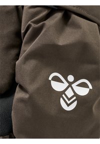 Brunt tyg med en slät textur som har ett vitt bi-emblem och geometriska detaljer. Designen är kompakt och funktionell.