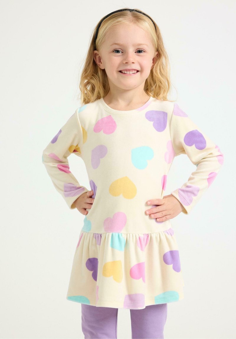 Langærmet kjole med en beige base, dekoreret med farverige hjerte-mønstre i pink, lilla og gul. Flæsekanterne tilføjer tekstur.