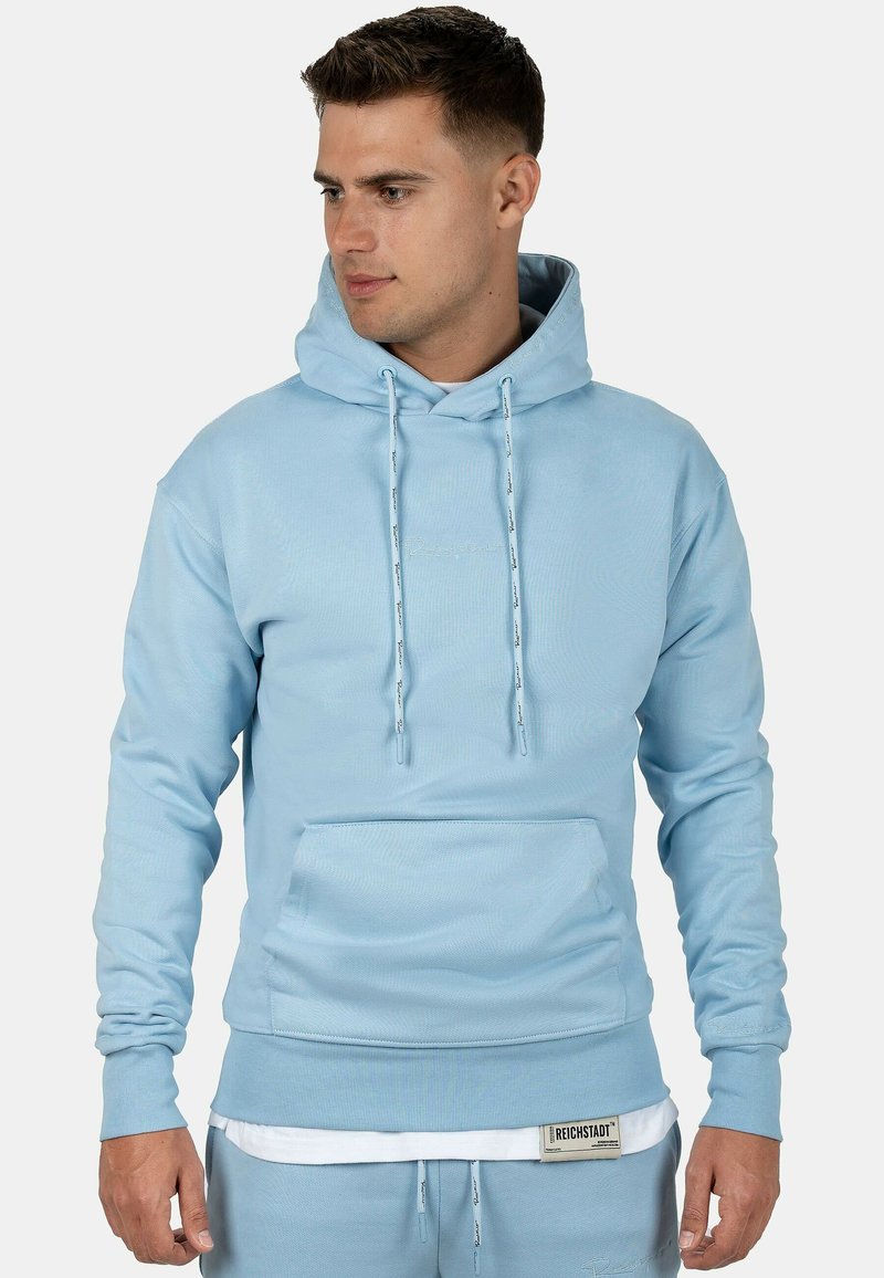 Hoodie azzurro chiaro realizzato in morbido tessuto, con tasca a canguro, cordini, polsini a coste e un delicato dettaglio del logo vicino all'orlo.