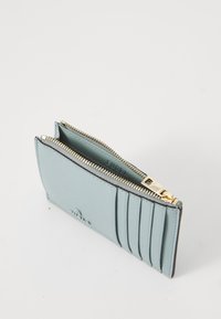 Light blue leather wallet with gold zipper, featuring card slots on one side and a smooth texture throughout. Compact and rectangular design.
