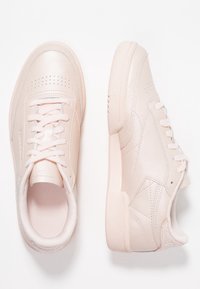 Różowe skórzane trampki z perforowanymi detalami, płaskimi sznurowadłami i fakturowanymi podeszwami. Zaokrąglony kształt z subtelnymi akcentami na pięcie.