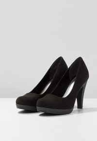 Chaussures à talons hauts en suede noir avec un bout rond, une plateforme texturée et un très talon lisse en contraste. Design simple sans motifs visibles.