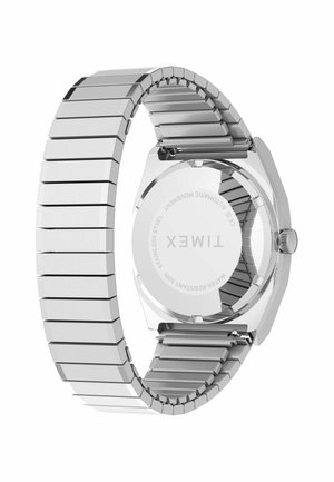 Ezüst színű rozsdamentes acél Timex karóra rugalmas szíjjal, hátlapján gravírozott márkanévvel és műszaki adatokkal.