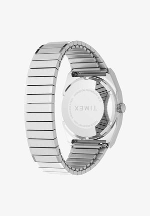 Srebrna ročna ura Timex iz nerjavečega jekla s prožnim paščkom, ki prikazuje vgravirano zadnjo stran ohišja z znamko in specifikacijami.