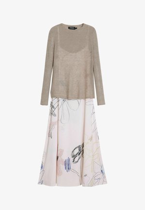 Beige lange mouwen gebreide trui over een witte midi rok met een meerkleurig abstract bloemenlijntekening ontwerp.