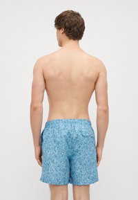 Meeste sinised ujumispüksid, millel on tekstuuriga mustriga kangas; elastne vöökoht; ja tagumine tasku nööbiga kinnitusega.