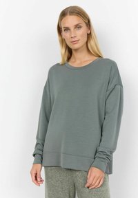 Lichtgrijze oversized sweatshirt met een ronde hals en lange mouwen, gemaakt van zachte stof, gecombineerd met grijze textuurbroek.