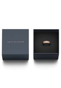 Ruusu kultainen sormus esillä tummansinisessä laatikossa, jossa on musta sisus; siinä on hienovaraisesti kaiverrettuna "DANIEL WELLINGTON" sormuksen nauhassa.