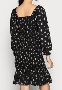 Czarna sukienka w kwiaty z marszczonym biustem, kwadratowym dekoltem, bufkami i falbaniastym dołem. Posiada kolorowe, małe wzory kwiatowe.