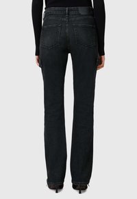 Jean en denim noir avec une coupe droite, doté de poches arrière, d'un léger effet délavé et d'une étiquette texturée à la ceinture.