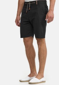 Black linen shorts with a drawstring waist featuring a woven design and leather accents, straight cut, and side pockets.