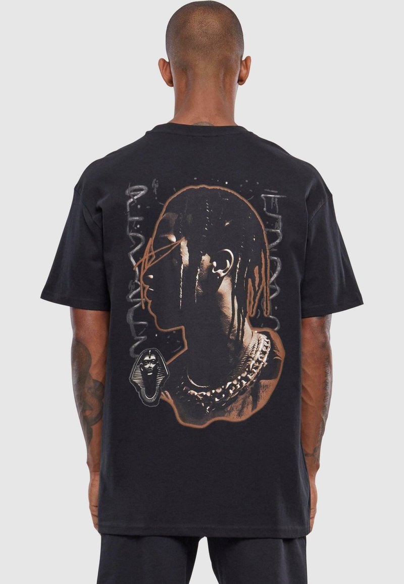Sort T-shirt med et grafisk profilportræt, kæderegulering og gamle egyptiske motiver i brune og gyldne nuancer.