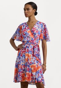 Vestido fluido com padrão floral, com mangas curtas e leves, em cores vibrantes de laranja, azul e roxo, com cintura ajustada e bainha solta.