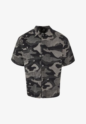 Félhosszú ujjú, gombos ing fekete és szürke kamuflázs mintával, textúrált anyagból készült. Jellemzője a hegyes gallér és az elülső gombok.