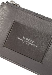 Gray leather wallet with a textured finish, featuring a smooth cardholder patch and embossed brand logo. Zipper closure at the top.