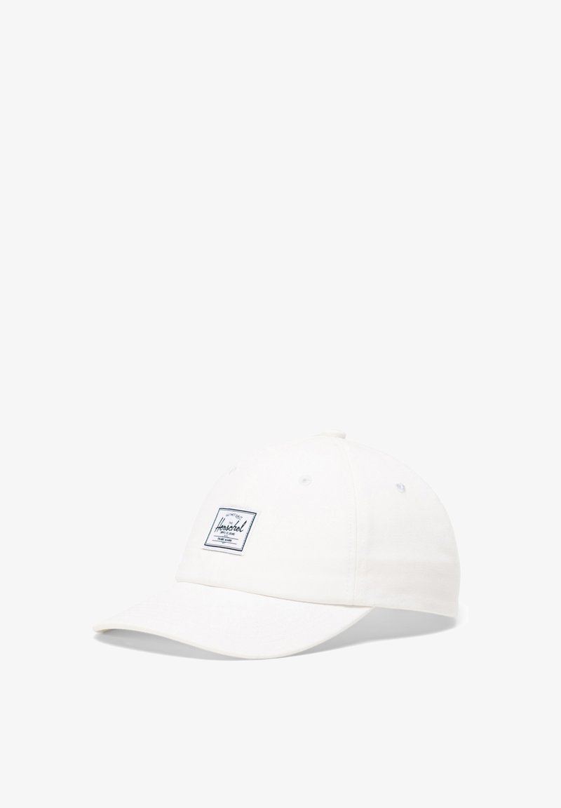 Biała bawełniana czapka z zakrzywionym daszkiem, z granatową naszywką z logo z przodu i otworami wentylacyjnymi na górze.