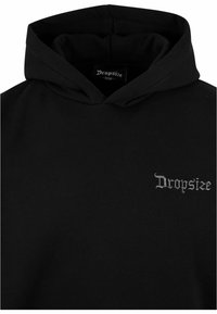 Schwarzer Hoodie mit einer frontalen Kängurutasche, weichem Baumwollmaterial und einem kleinen, strukturierten "Dropsize"-Logo in Grau auf der Brust.