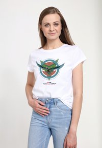 Camiseta blanca de algodón con un diseño gráfico que presenta una figura alada, acentos circulares en verde azulado, verde y coral, y el texto "Captain America".