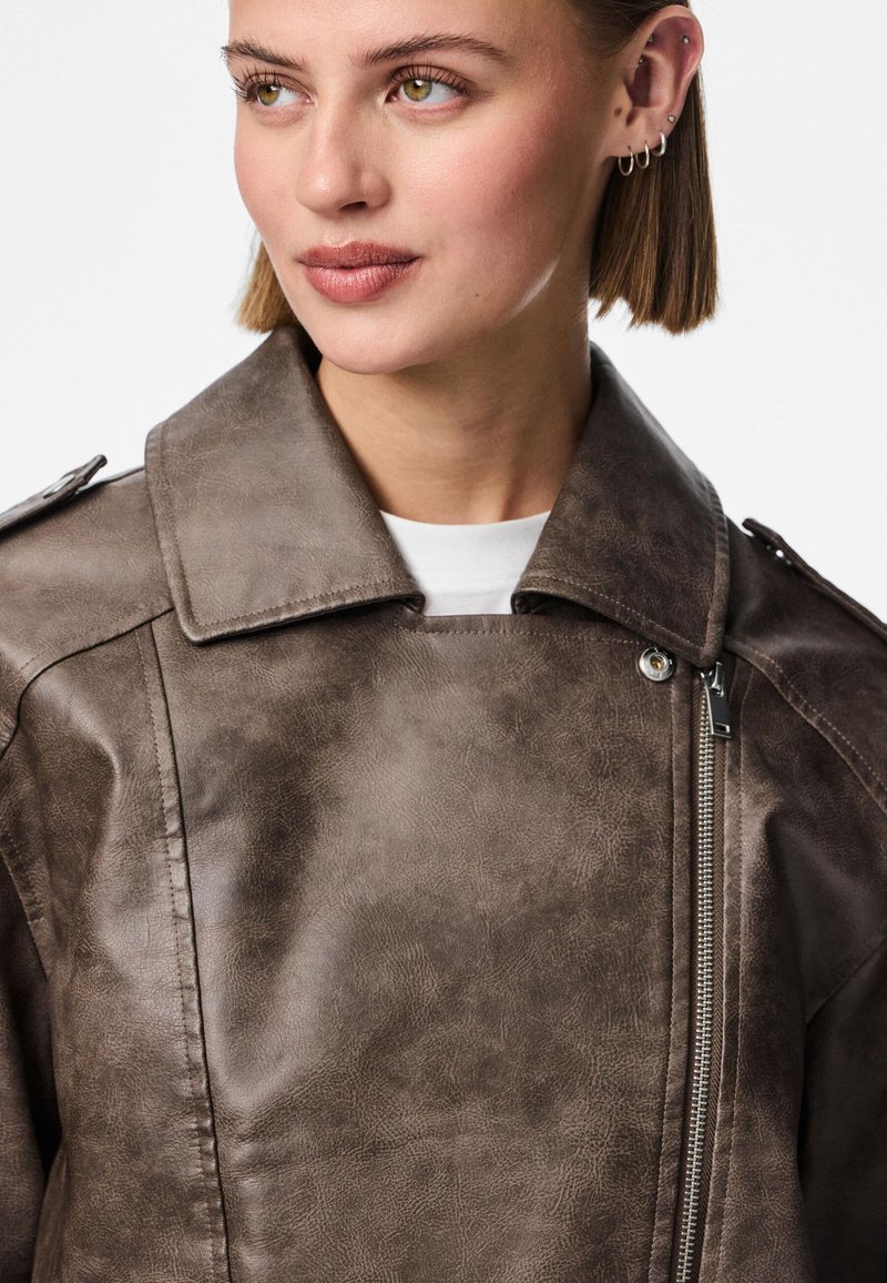 Giacca in ecopelle marrone con colletto strutturato, chiusura con zip, superficie testurizzata e funzionali epaulettes sulle spalle.