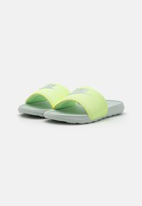 Nike sandaler med lys gul-grønn syntetisk overdel og grå gummisåle. Har en teksturert stropp og subtil merking.
