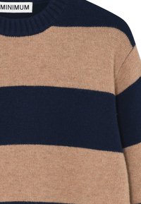Pletený sveter s striedajúcimi sa námorníckymi modrými a béžovými horizontálnymi pruhmi, s rebrovaným okrúhlym výstrihom a mäkkou textúrou. Minimalistická nálepka.