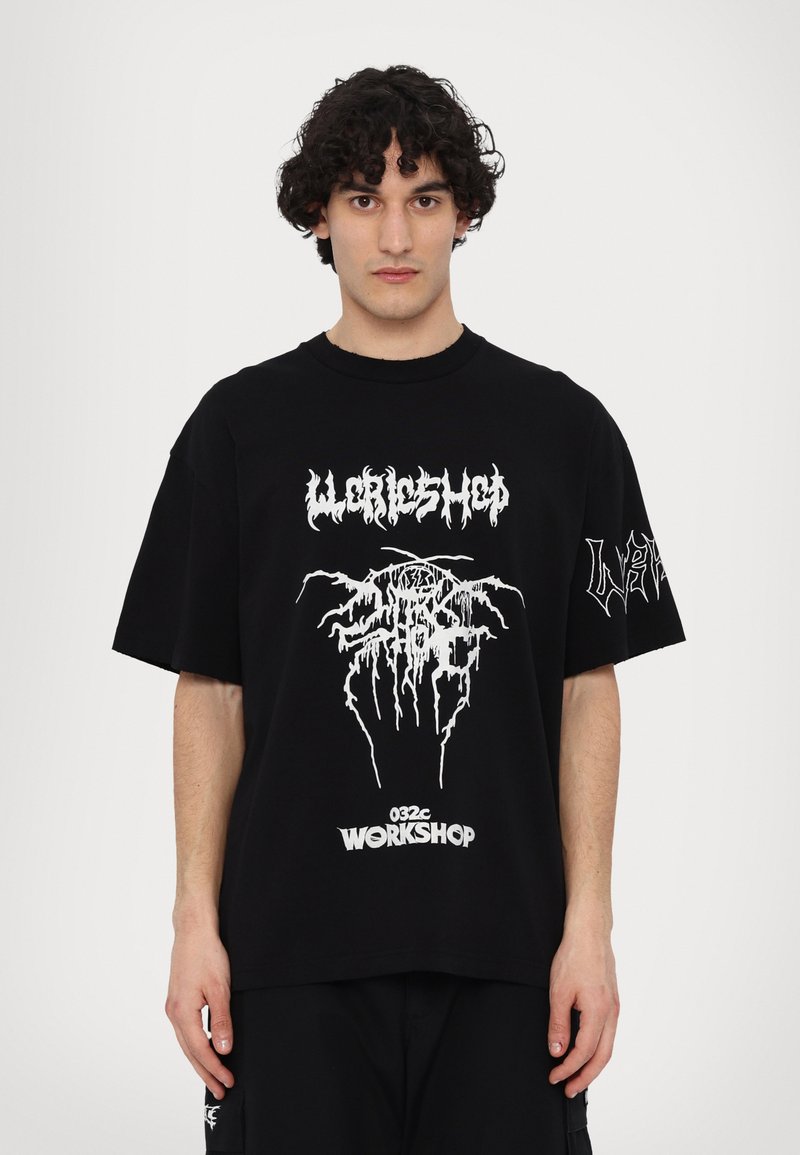 Sort oversized T-shirt lavet af bomuld, med hvid grafisk tekst og design på fronten og venstre ærme. Løs pasform og korte ærmer.