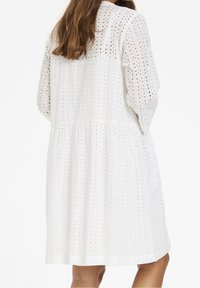 Weißes Baumwollkleid mit strukturiertem Blumenmuster, langen puffärmel, gerafftem Taillenbereich und knie-langer, ausgestellter Silhouette.