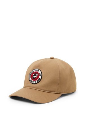 Beige Baseballkappe mit einem runden Aufnäher, der einen Hund mit Kopfhörern und dem Text "Hugo Cane Wine & Music Records" zeigt.