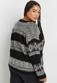 Schwarz-weiß gestrickter Pullover mit geometrischen Mustern, Zopfmuster und lockerer Passform mit gerippten Bündchen und Saum.
