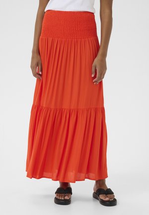 Lange, gelaagde rok in felle oranje, gemaakt van lichtgewicht stof. Heeft een smocked tailleband en een vloeiende silhouet. Gecombineerd met zwarte sandalen.