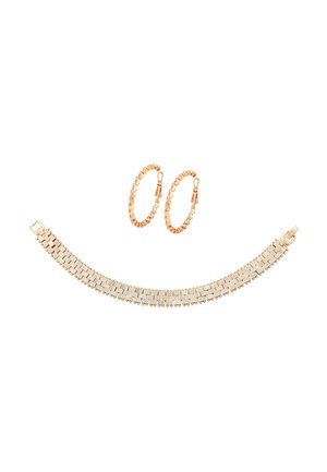 Złote teksturowane kolczyki koła połączone z szeroką złotą bransoletką o wzorze splecionych elementów i zapięciem na zatrzask.