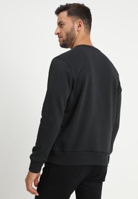 Black sweatshirt with a crew neck, ribbed cuffs, and a straight hem. Made from a soft cotton blend, featuring a smooth texture.